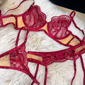 Detail shot of a dark red embroidery lace lingerie set with garters on white fur