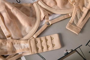 Détail du soutien-gorge en dentelle chair avec broderie florale et anneau doré