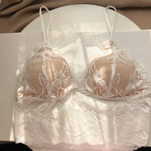 Detailed close-up of white floral lace bralette with thin straps and natural sunlight