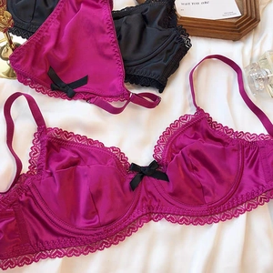 Detailed view of elegant satin and lace bras in rose red and black with bow accents