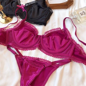 Detailed close-up of fuchsia satin and heart lace lingerie set on white silk background