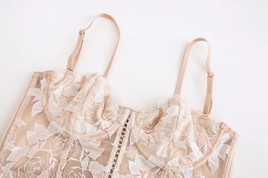 Détail de la broderie florale et de la dentelle délicate sur ce bustier rose poudré