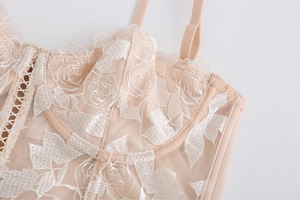 Gros plan détaillé de la broderie florale sur un corset en dentelle pêche et mesh