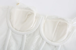 Close-up of white lace corset with fishbone support and delicate mesh floral patterns