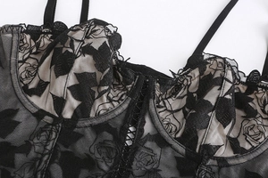 Gros plan sur un bustier en dentelle florale noire avec broderie rose et détails en résille