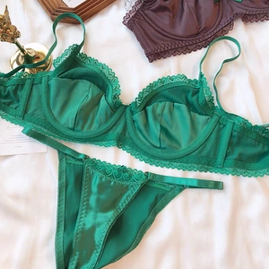 Close-up of emerald green satin lingerie with delicate heart lace trim and underwire support