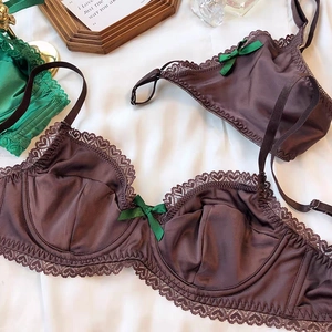 Detailed close-up of brown satin and lace bra set with a contrast green silk bow detail