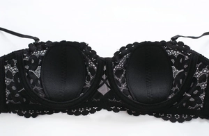 Detail of floral lace embroidery and soft inner padding on this black half cup bra