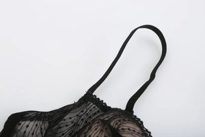 Detail of black lace lingerie showing fine straps, sheer mesh, and polka dot textures