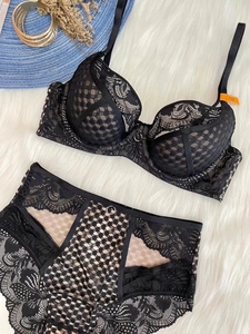 Flat lay of black lace lingerie set with high waist panty on white plush rug