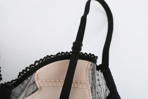Close-up of black floral lace bra with adjustable straps and fine mesh polka dot texture
