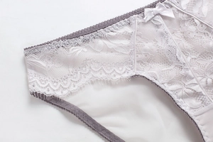 Close-up of delicate white lace embroidery and small bow detail on low-rise panties
