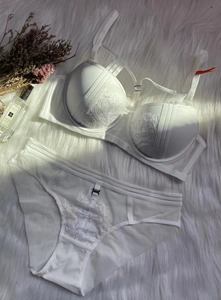 Flat lay of white lace push-up bra set with matching mesh briefs on soft plush background