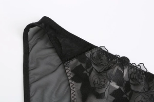 Detailed macro view of black floral rose embroidery on delicate mesh lace fabric