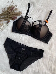 Close-up detail of black lace push-up bra set and matching panties on white plush background