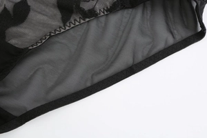 Detail of black hexagonal mesh fabric featuring elegant floral flocking and neat edge stitching