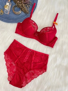 Flat lay of red lace lingerie set with floral patterns on white plush background