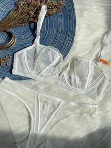 Detailed flat lay of white French lace lingerie set with floral embroidery and mesh details
