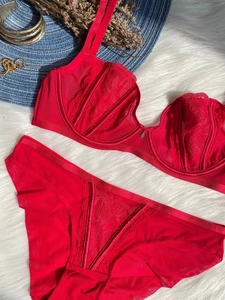 Detailed flat lay of red lace and mesh lingerie set on a white plush rug with accessories