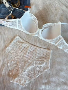 Flat lay of white lace lingerie set with underwire bra and high waist panties on plush rug