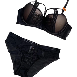 Completo intimo sexy in pizzo nero con reggiseno push-up e slip a rete su fondo bianco