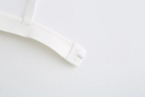 Close-up of single metal hook fastener and fine stitching on white lace bralette