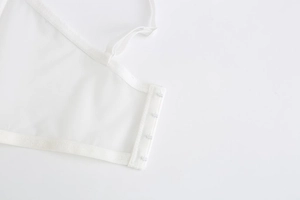 Detail shot of four-row hook-and-eye closure on white lace bra with fine stitching