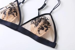 Détail de broderie florale bleue sur résille beige de ce soutien-gorge sans armature