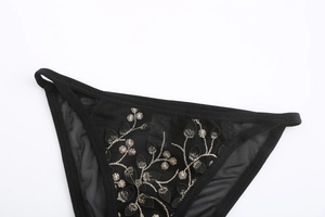 Detailed macro view of black sheer mesh panties with exquisite gold floral embroidery