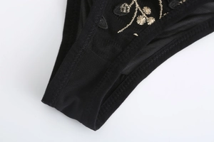 Close-up of black mesh fabric with gold floral embroidery on low-rise lace panties