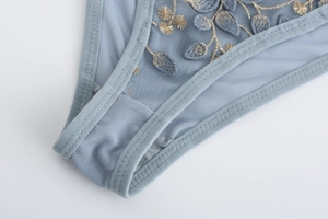 Close-up of light blue lace embroidery on breathable sheer mesh fabric underwear