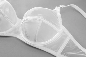 Detail of white mesh bra featuring sheer fabric and geometric structural stitching
