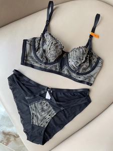 Flat lay of black lace lingerie set with floral embroidery and gold metal details