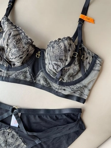 Close-up of black floral lace embroidery details and gold hardware on lingerie set