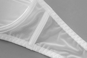 Close-up of white breathable mesh fabric and precise stitching on French style lingerie