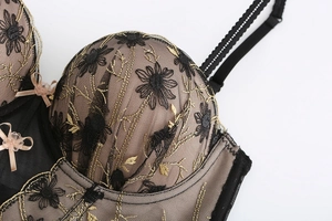 Close-up of exquisite floral lace embroidery and delicate bow on a black mesh bra