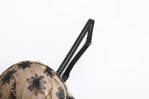 Detail of floral lace embroidery with gold outlines and elegant black scalloped straps