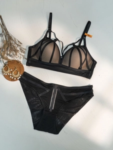 Flat lay of black mesh lingerie set with geometric crisscross straps and 75B size tag