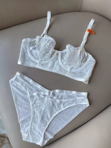 Flat lay of white embroidered lace lingerie set with mesh details and size 75B tag