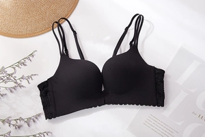 Detail of seamless black wireless bra with lace wings and double straps on white background