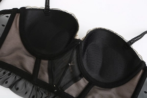 Macro shot of black polka dot mesh bra showing detailed gold stitching and sheer fabric