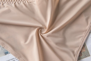 Detailed close-up of nude high-stretch smooth fabric with precision double stitching