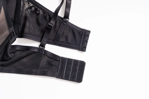 Detail of black lace bra showing three-row hook closure and adjustable straps on mesh fabric