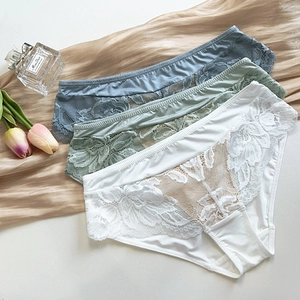 Vue à plat de trois culottes en dentelle blanche, verte et bleue avec broderies florales