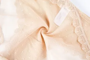 Vue détaillée du tissu en maille beige avec pois et bordures en dentelle ondulée douce