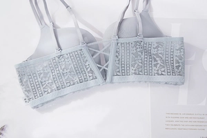 Detail of light blue lace bra featuring crisscross back straps and floral patterns
