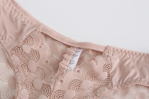 Détail de culotte en dentelle rose avec breloques en cœur et étiquette de composition