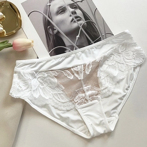 Détail de culotte en dentelle blanche à broderies florales avec bords festonnés soyeux