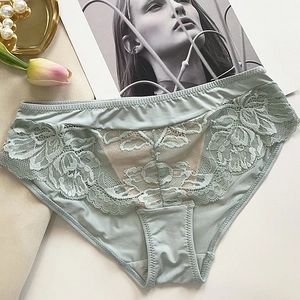 Détail de culotte en dentelle vert clair avec broderie florale sur plateau déco