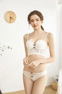 Detailed front view of a white lace bustier lingerie set with small black bow accents